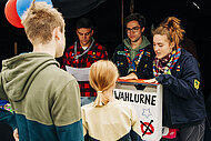 Jugendliche und Wahlhelfer:innen an der Urne zur U18-Landtagswahl